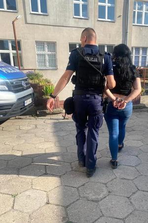 Policjant prowadzi zatrzymaną kobietę