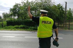 Policjant uniesioną ręką zatrzymuje samochód do kontroli