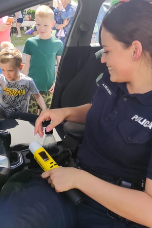 Policjantka w radiowozie przedstawia dzieciom wyposażenie