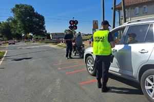 Policjant rozmawia z motocyklistą, a strażnik ochrony kolei z kierowcą osobówki