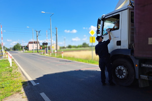 Policjant wręcza ulotkę kierowcy ciężarówki