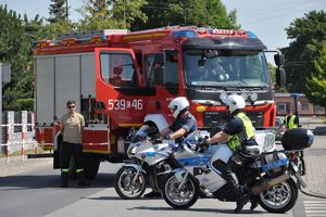 Policyjni motocykliści stoją obok wozu strażackiego