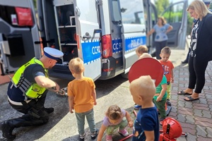 Policjant pokazuje dzieciom lustro służące do kontroli podwozia