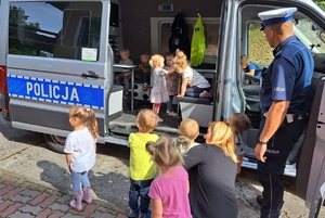 Policjant ruchu drogowego prezentuje dzieciom radiowóz wypadkowy