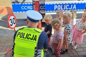Policjant drogówki rozmawia z dziećmi o znakach drogowych