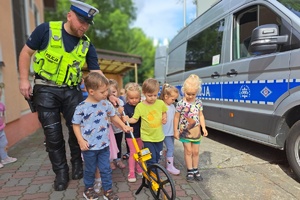 Policjant wspólnie z dziećmi prowadzi wózek mierzący odległość