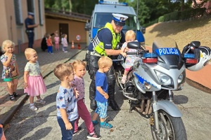 Policjant wsadza na motocykl dziewczynkę