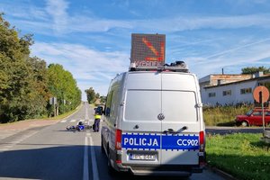 na zdjęciu radiowóz policyjny oraz policjantka wykonująca czynności na miejscu zdarzenia.