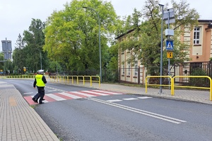 Funkcjonariusze przechodzą przez jezdnię w okolicy szkoły