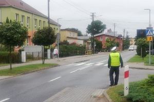 Policjant sprawdza oznakowanie przejścia przy szkole