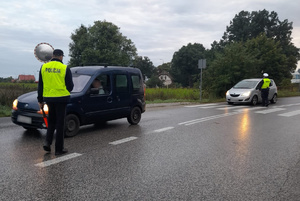 Policjant podchodzi do zatrzymanego samochodu