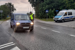 Policjant stoi przy kontrolowanym aucie, dokonuje kontroli trzeźwości kierowcy