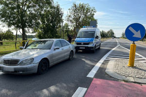 Zatrzymany przy użyciu kolczatki drogowej mercedes. Na zdjęciu widać uszkodzone opony pojazdu i stojący za nim radiowóz