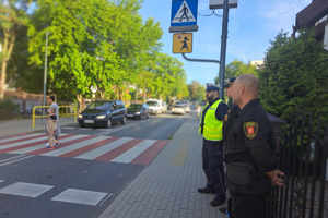 Policjant wspólnie z funkcjonariuszami straży miejskiej obserwują przejście dla pieszych