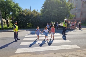 Dzieci wraz z policjantami ćwiczą bezpiecznie przechodzenie przez jezdnię