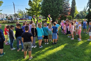 Policjanci prowadzą pogadankę z dziećmi przed budynkiem szkoły