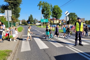 Policjanci zabezpieczają drogę podczas praktycznej lekcji przechodzenia dzieci przez jezdnię