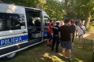 Uczestnicy pikniku rozmawiają z policjantem ruchu drogowego