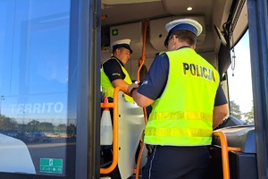 Mundurowi stoją w wejściu autobusu i rozmawiają z kierowcą