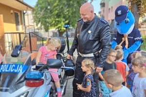 Na służbowym motocyklu policjanta siedzi dziewczynka