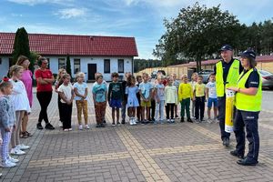 Policjanci na placu apelowym rozmawiają z dziećmi