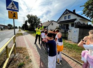 Uczniowie wraz z policjantami zbliżają się do przejścia dla pieszych