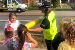 Policjantka pokazuje za pomocą tuby działanie odblasków