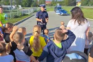 Policjant rozmawia z najmłodszymi na dziedzińcu przedszkola