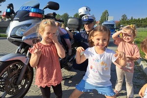 Przedszkolaki stoją przy motocyklu i policjancie