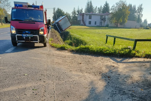 Wóz strażacki i widok z tyłu przewróconej do rowu ciężarówki