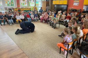 Policjant prezentuje przedszkolakom pozycję obronną przed atakiem psa