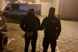 Policjant prowadzi do radiowozu mężczyznę