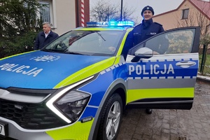 Policjant stoi przy otwartych drzwiach nowego radiowozu