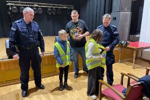 Policjanci pomagają założyć dzieciom kamizelki odblaskowe