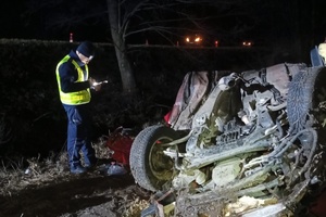 Policjant ruchu drogowego prowadzi oględziny rozbitego pojazdu