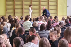 Policjant rozmawia na środku sali z dziewczynką