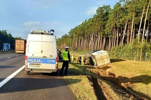 Samochód ciężarowy leżący w rowie, obok policjant wykonuje czynności służbowe