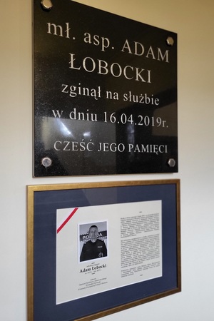 Tablica pamiątkowa zmarłego policjanta oraz tablica z jego zdjęciem