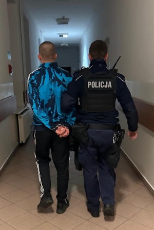 Policjant prowadzi zatrzymanego mężczyznę