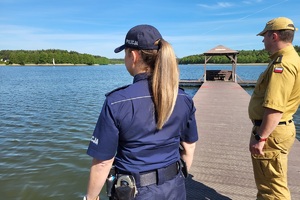 Funkcjonariusze stoją na pomostku, spoglądają w kierunku jeziora