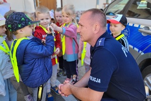 Policjant kuca, rozmawia z dziećmi