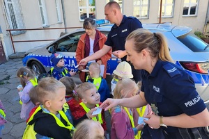 Policjantka wręcza odblaski dzieciom