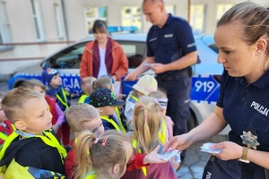 Policjanci wręczają odblaski dzieciom