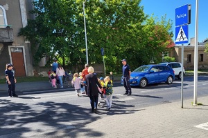 Dzieci przechodzą przez jezdnie w eskorcie policjantów