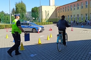 Chłopiec jedzie rowerem, policjant idzie za nim