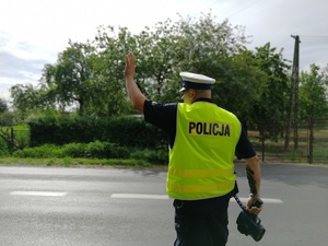 Policjant trzyma radar w ręku, drugą daje znak do zatrzymania