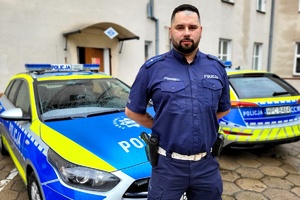 mł. asp. Marcin Ignatowski stoi przy radiowozie