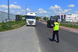 Policjant idzie jezdnią, szuka śladów blokowania kół