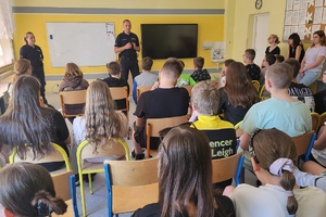 Policjant prowadzi spotkanie z uczniami w sali lekcyjnej