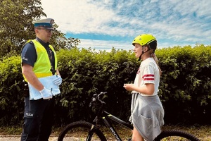 Policjant rozmawia z dziewczynką siedzącą na rowerze